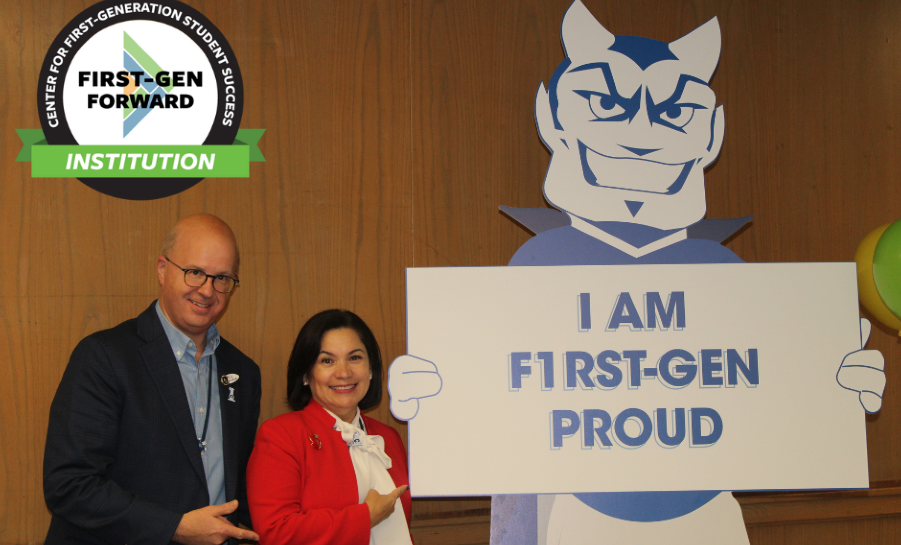Two staff members standing with the school mascot