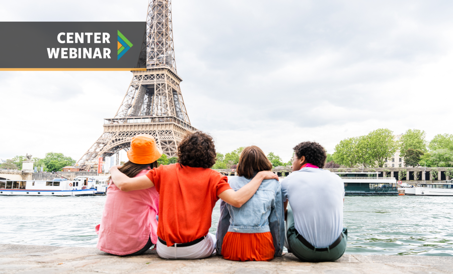 Four students looking at the Eiffel Tower while seated at the edge of a river