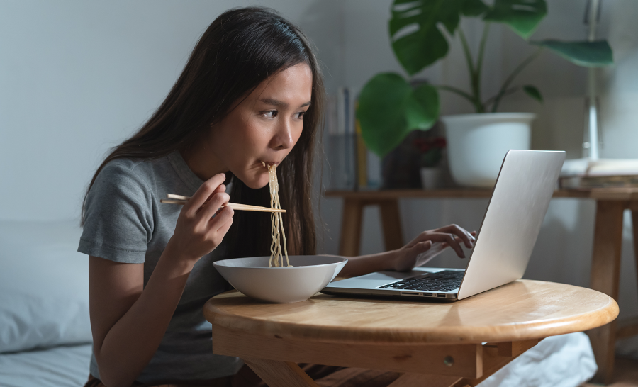 student eating and studying at laptop