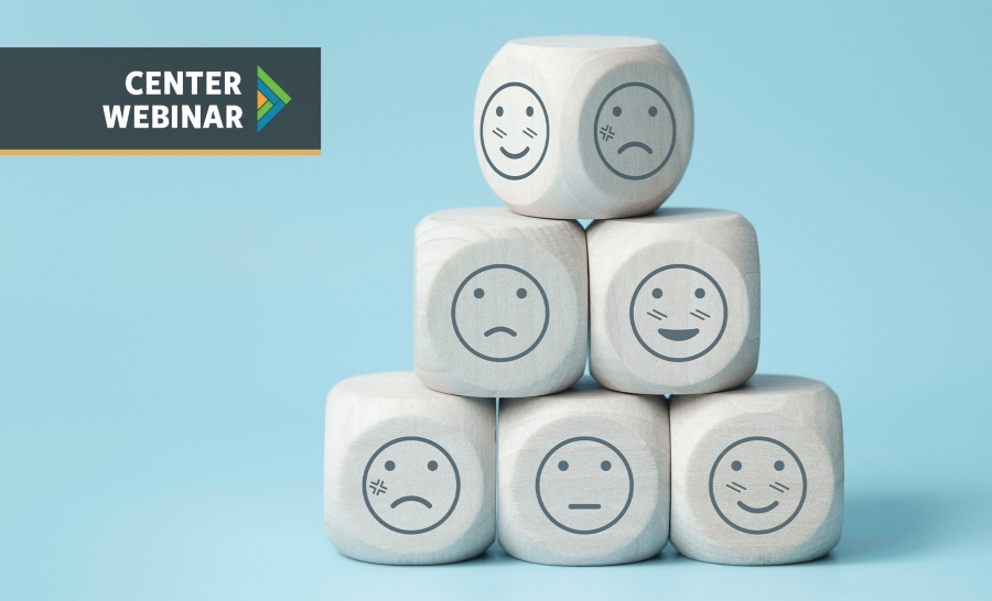 White dice stacked in a pyramid with smiley faces demonstrating different emotions on each side in front of a teal background