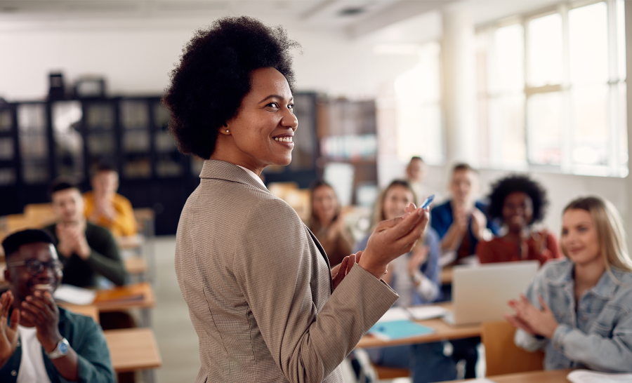 Black female professor teaching students in classroom while smiling