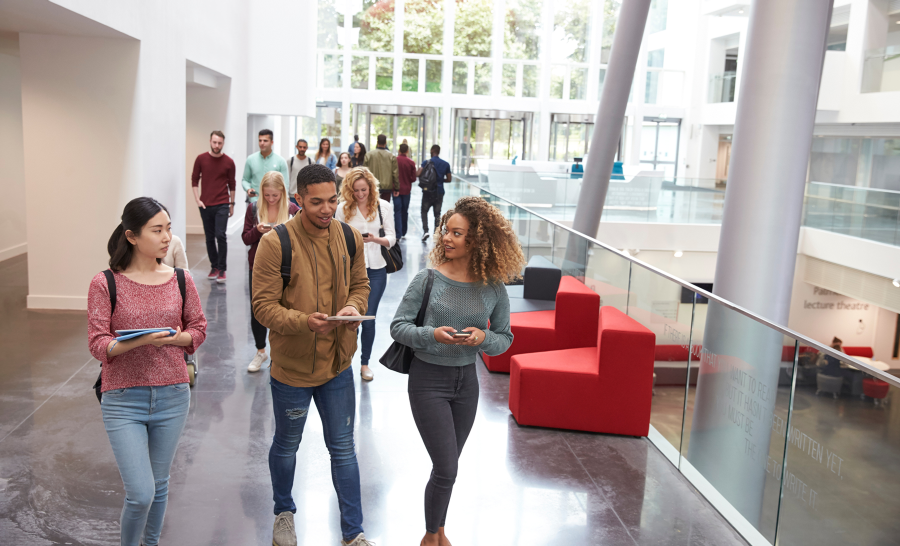 Diverse students walking inside campus building