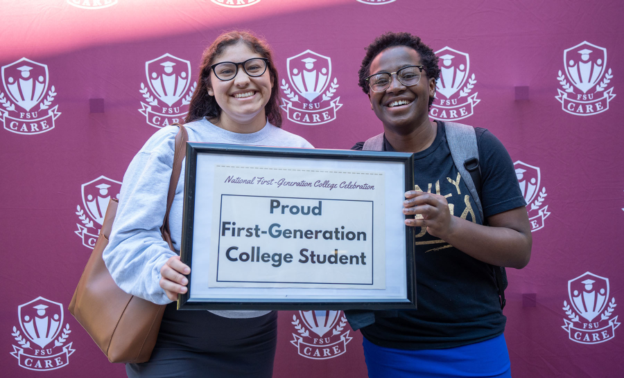 Two students holding framed sign reading 
