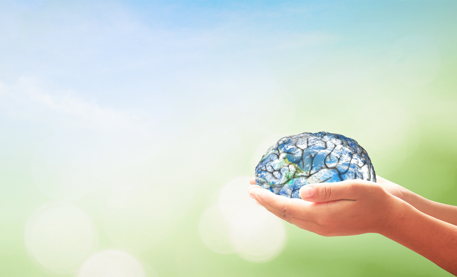 Woman's hands cradling brain resembling the Earth in front of a blue and green background