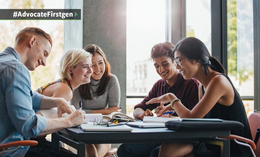 Five students sitting at a table in well-lit atrium smiling while one of them tells a story