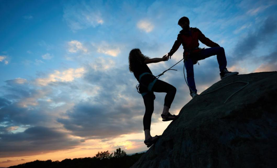Silhouette of students rock climbing at sunset