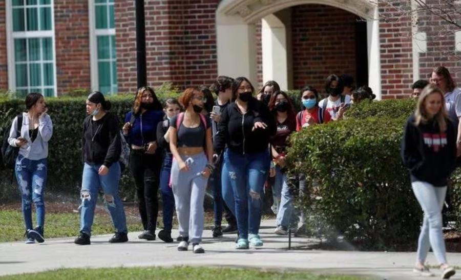 Group of students talking as they walk out of a campus building between classes