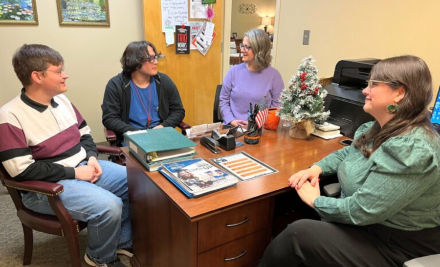 Two usculum students speaking with TRIO personnel in office with wooden desk