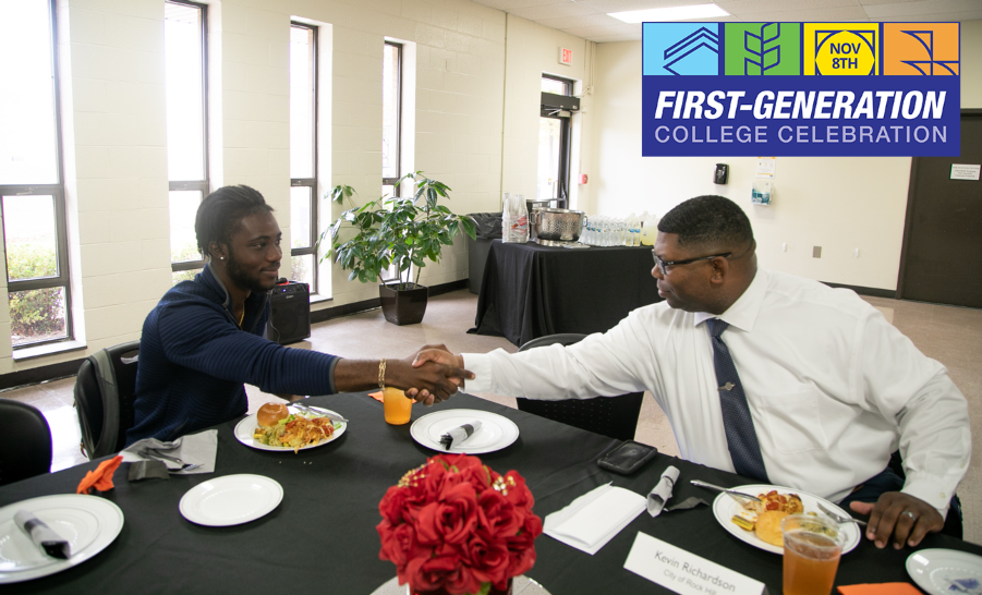 Student and staff member shaking hands across table set for meal
