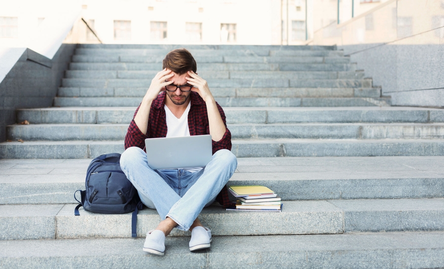frustrated male student sitting on stairs