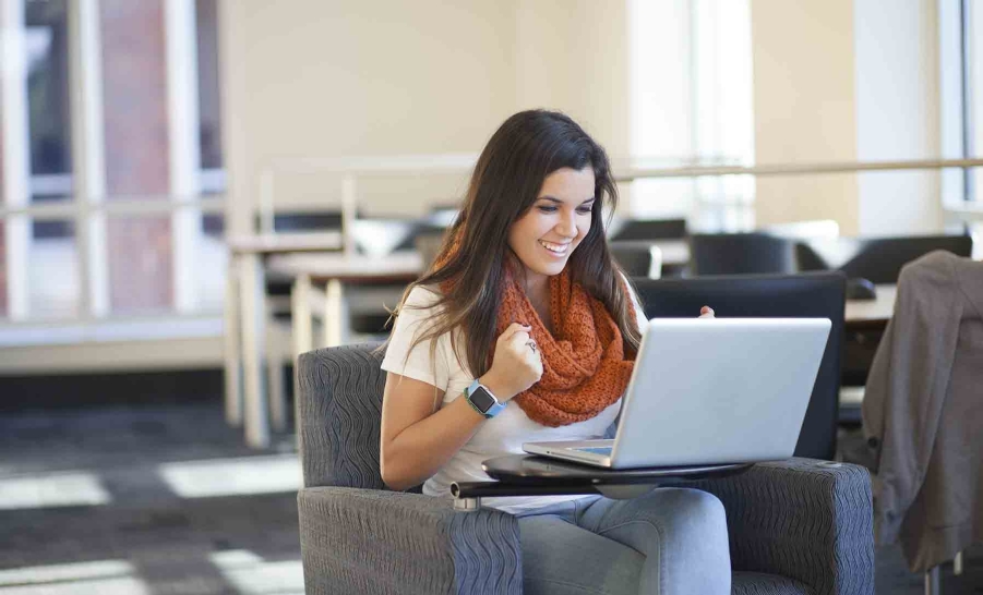 latino college student happy on laptop