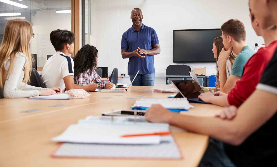 male professor blue polo talking to students