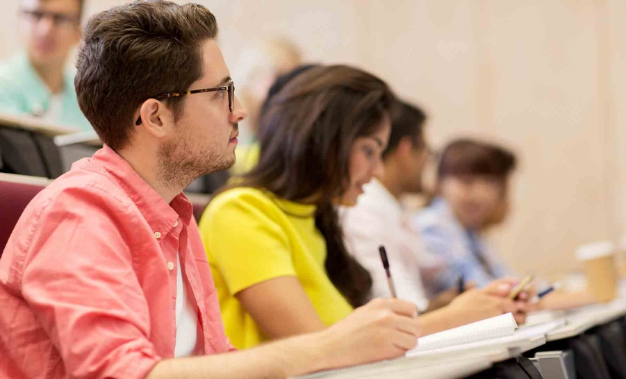 male student pink button up in class