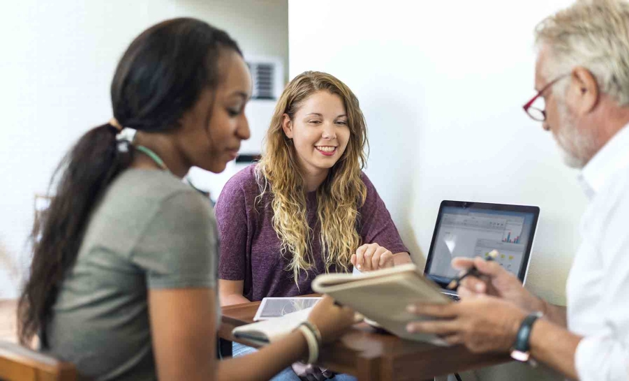 two female students sitting with male professor