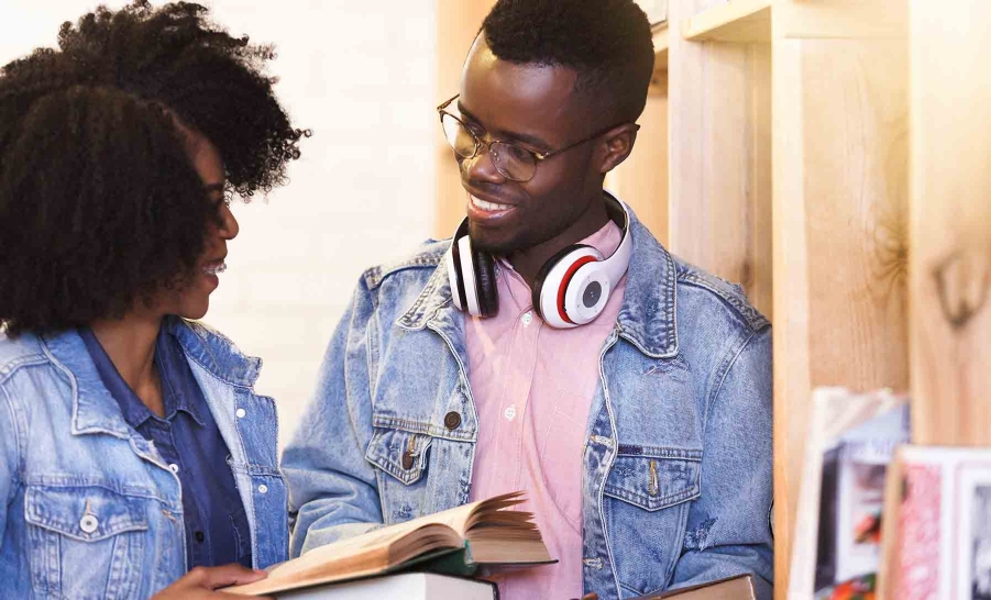 two happy students reading in library